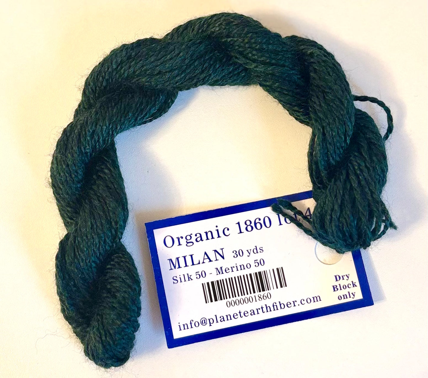 Dark green skein of yarn with a label on a white background