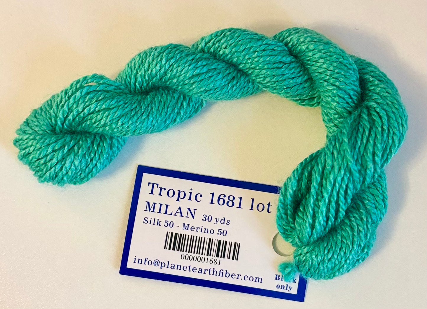 Turquoise skein of yarn with a label on a white background